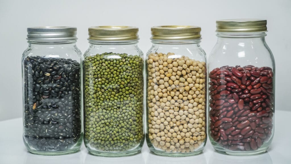 Various Pulses In Mason Jars On Table Against White Background